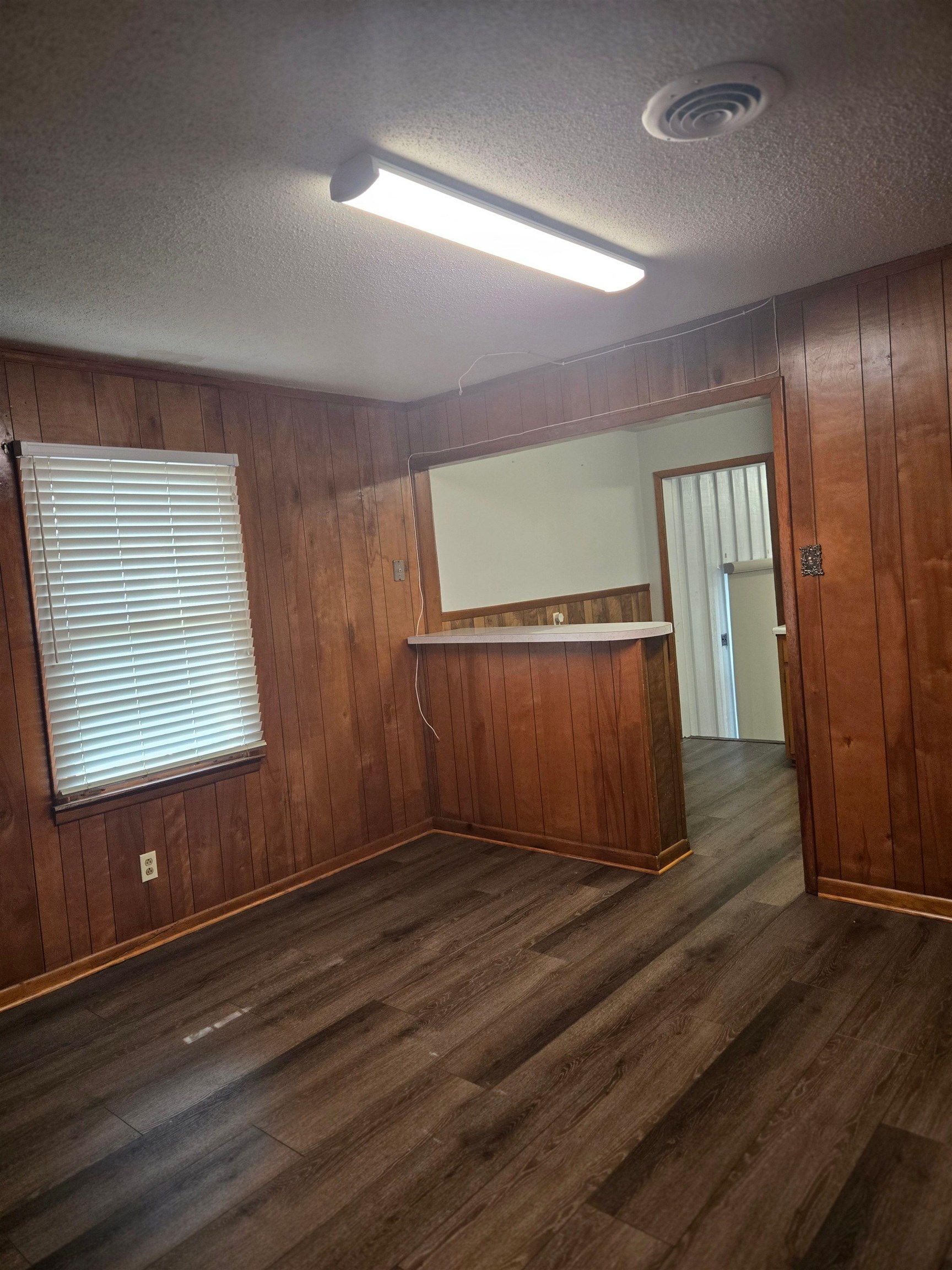 6855 Raleigh Lagrange Road Memphis, TN 38134 - Photo 8 of 13 Unfurnished room featuring wooden walls, dark wood-type flooring, and a textured ceiling