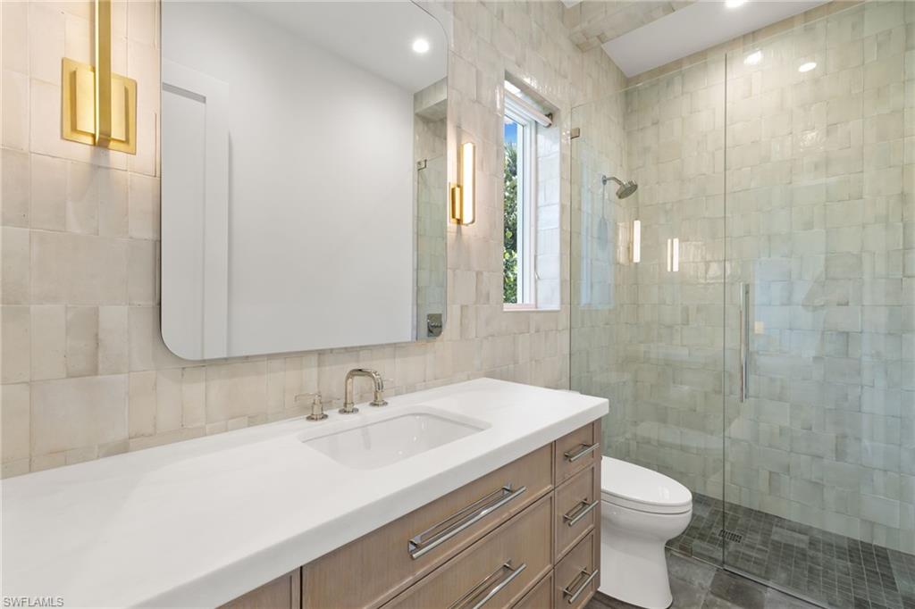 660 Wedge Drive Naples, FL 34103 - Photo 17 of 22 a bathroom with a sink a toilet a shower and a mirror