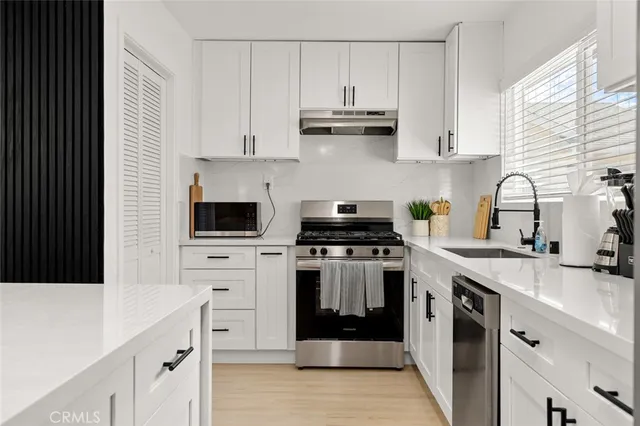 a kitchen with cabinets appliances a sink and a window