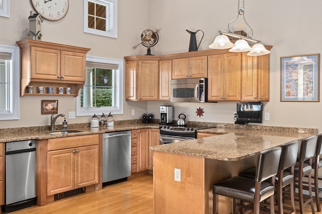 17 Summersweet Circle, Unit 22 Hanover, MA 02339 - Photo 6 of 42 a kitchen with stainless steel appliances granite countertop a stove a sink dishwasher and a microwave oven with wooden cabinets
