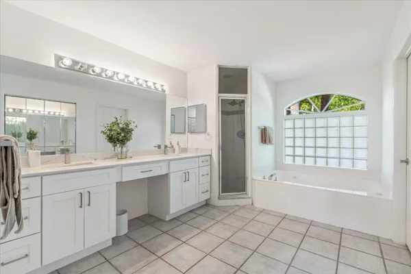 a spacious bathroom with a granite countertop sink a mirror and a bathtub