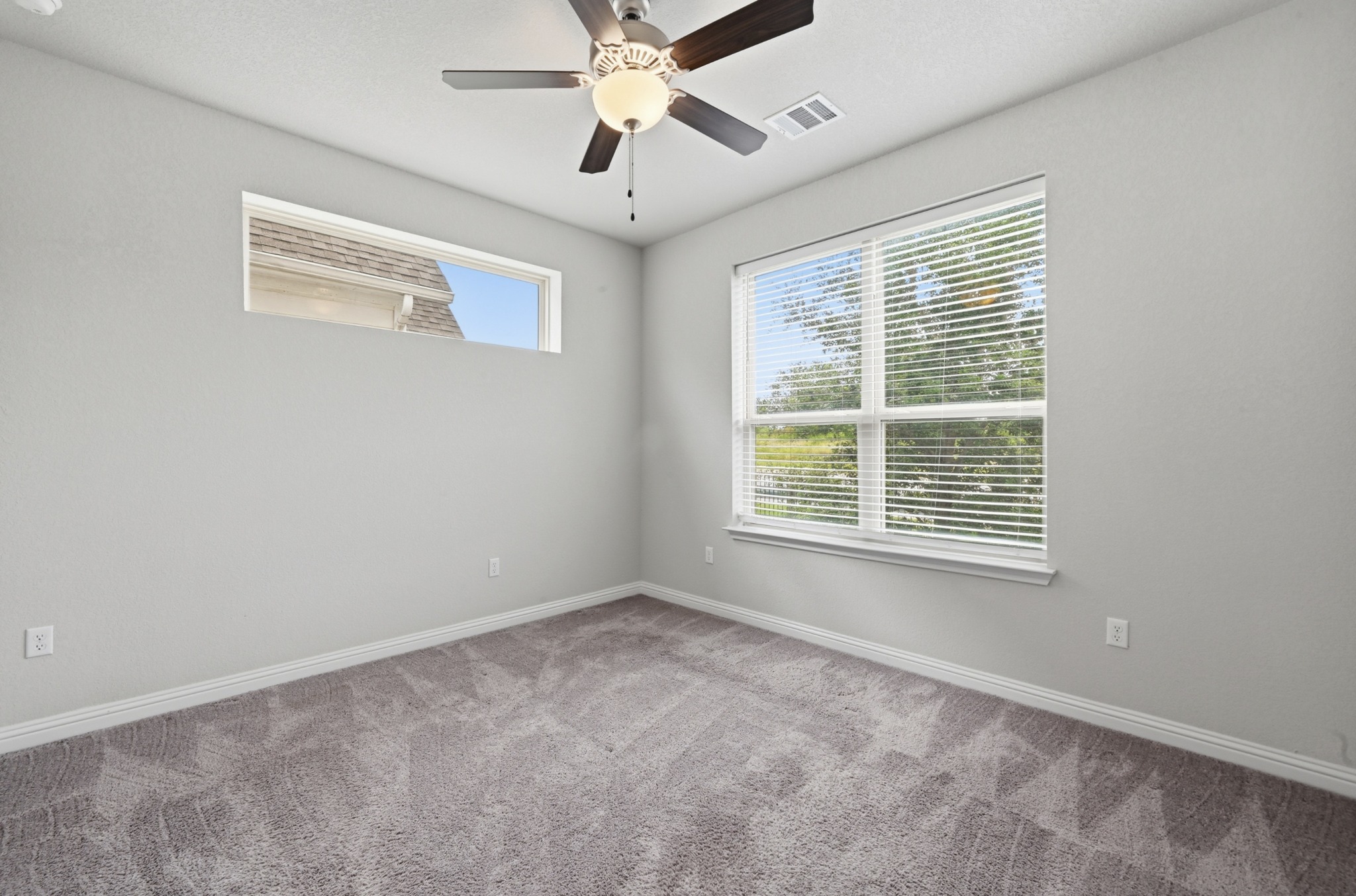 8201 Frida Bend Austin, TX 78744 - Photo 20 of 29 A well-lit room offering plush carpeted floors and a cooling ceiling fan for comfort.