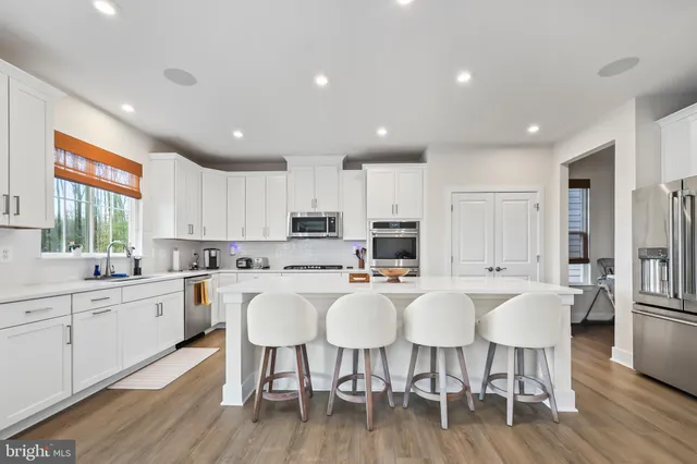 a large kitchen with kitchen island a dining table chairs and white cabinets