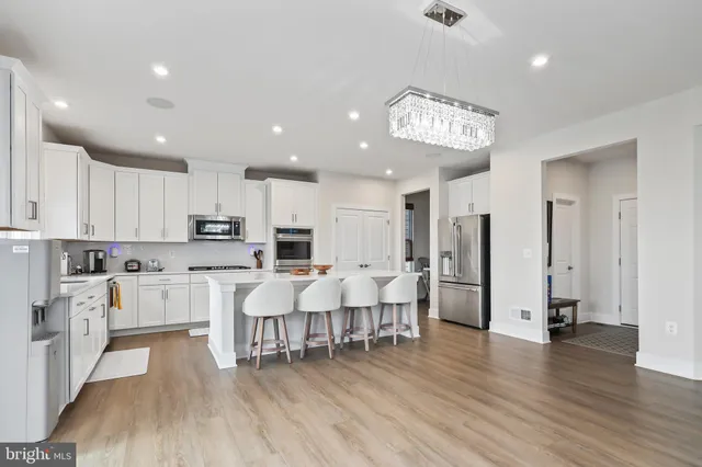 a open kitchen with white cabinets stainless steel appliances and wooden floor