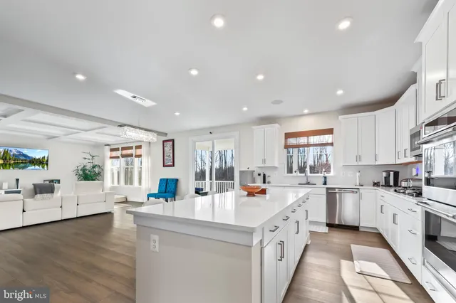 a large white kitchen with a lot of counter space and wooden floor
