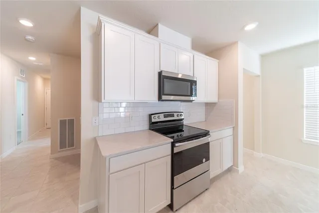 a view of a kitchen with a sink and dishwasher a refrigerator with white cabinets