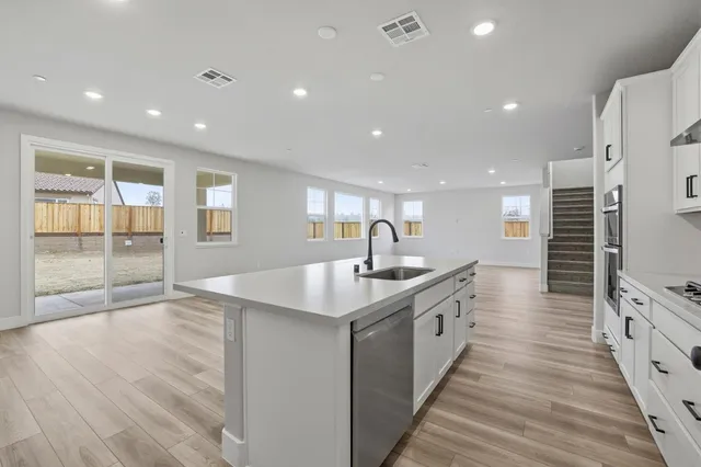 a large kitchen with stainless steel appliances granite countertop a lot of counter space and wooden floor