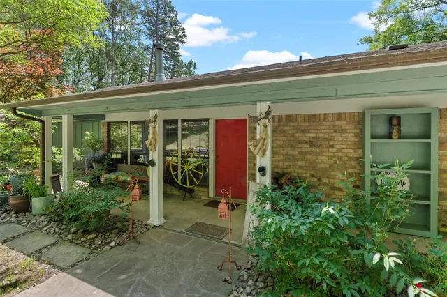 a view of a porch with potted plants and floor to ceiling window