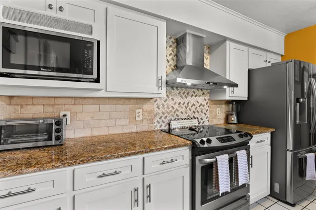 a kitchen with stainless steel appliances granite countertop white cabinets and a stove a oven with wooden floors