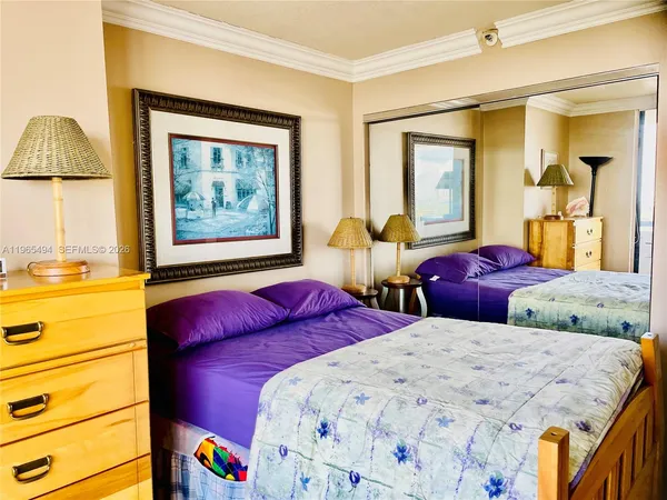 a bedroom with two beds and a lamp on dresser