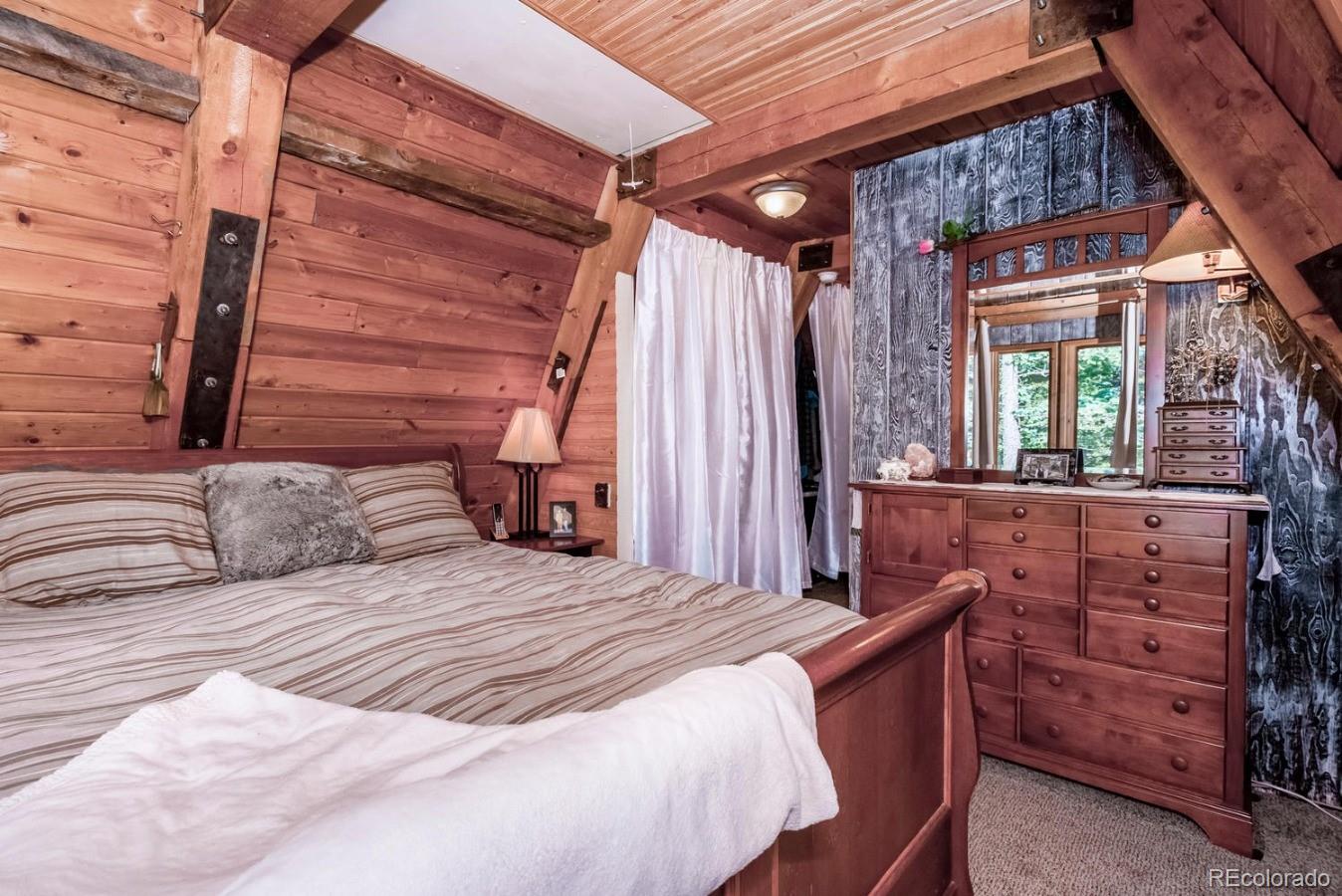 12802 Upper Ridge Road Conifer, CO 80433 - Photo 14 of 27 a bedroom with a bed and a mirror