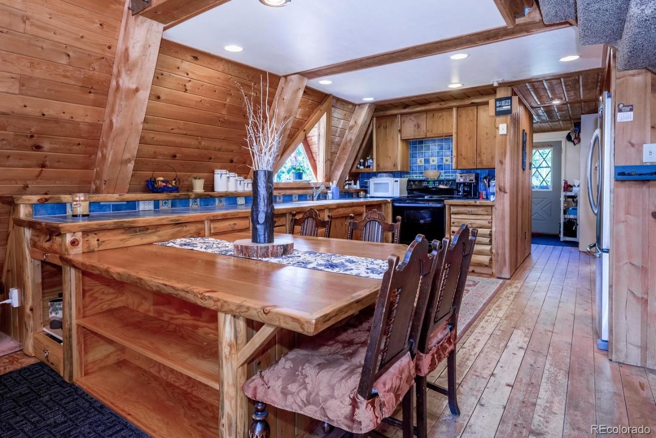 12802 Upper Ridge Road Conifer, CO 80433 - Photo 5 of 27 a dining room with a wooden table and chairs