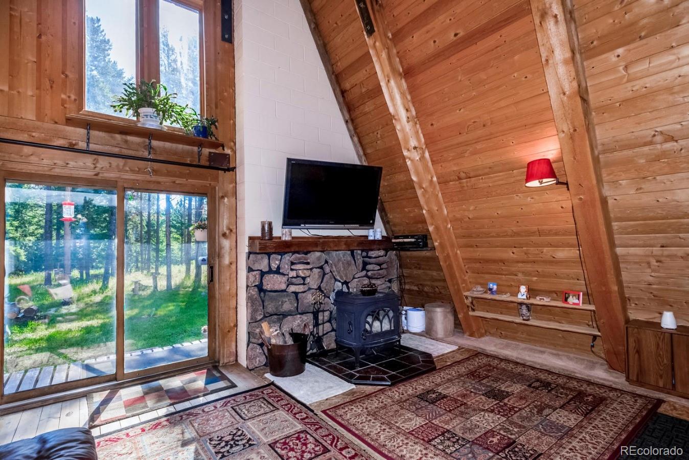 12802 Upper Ridge Road Conifer, CO 80433 - Photo 7 of 27 a living room with fireplace furniture and a floor to ceiling window