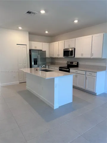 a kitchen with stainless steel appliances a sink a stove a microwave a center island and cabinets