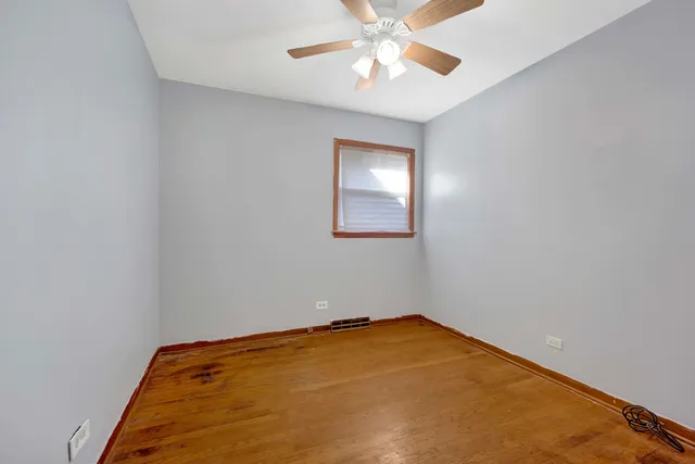 an empty room with a chandelier fan and a window