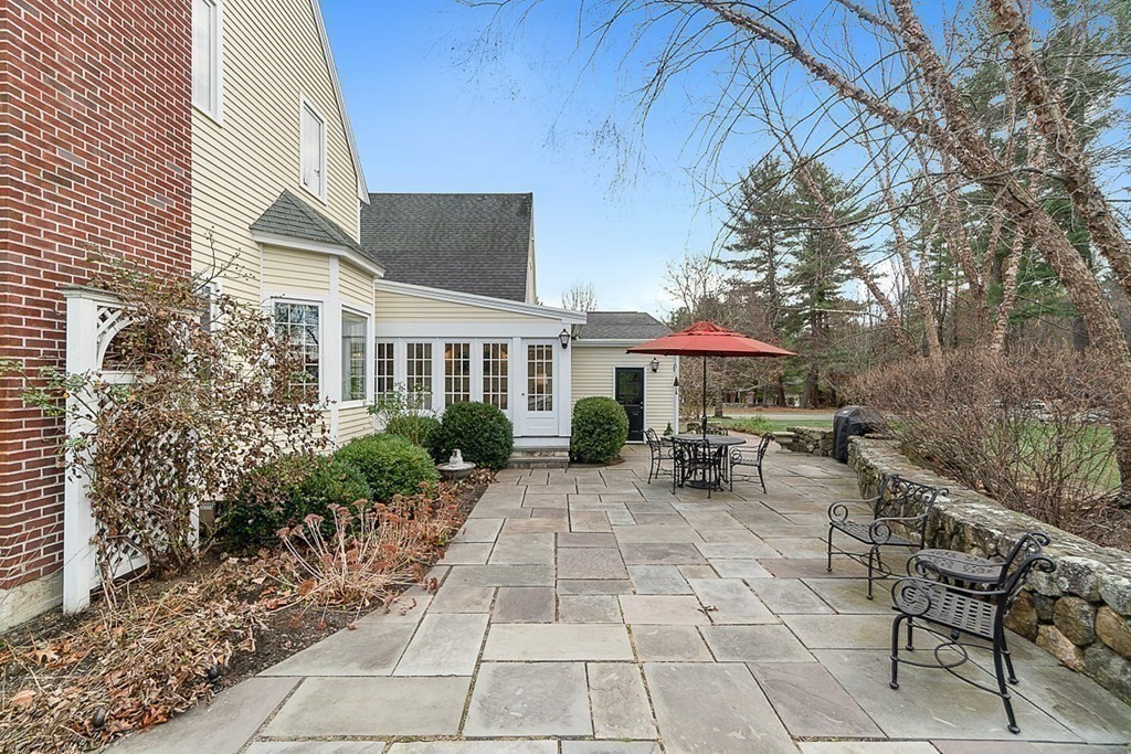 853 Strawberry Hill Road Concord, MA 01742 - Photo 38 of 41 a view of a patio with table and chairs under an umbrella with a barbeque