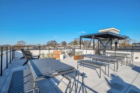 a view of a roof deck with table and chairs under an umbrella with wooden floor