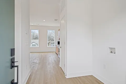 a view of a hallway with wooden floor and a bathroom