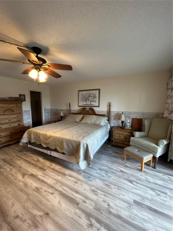 4775 Cove Circle, Unit 1202 Madeira Beach, FL 33708 - Photo 20 of 32 a spacious bedroom with a bed and a ceiling fan