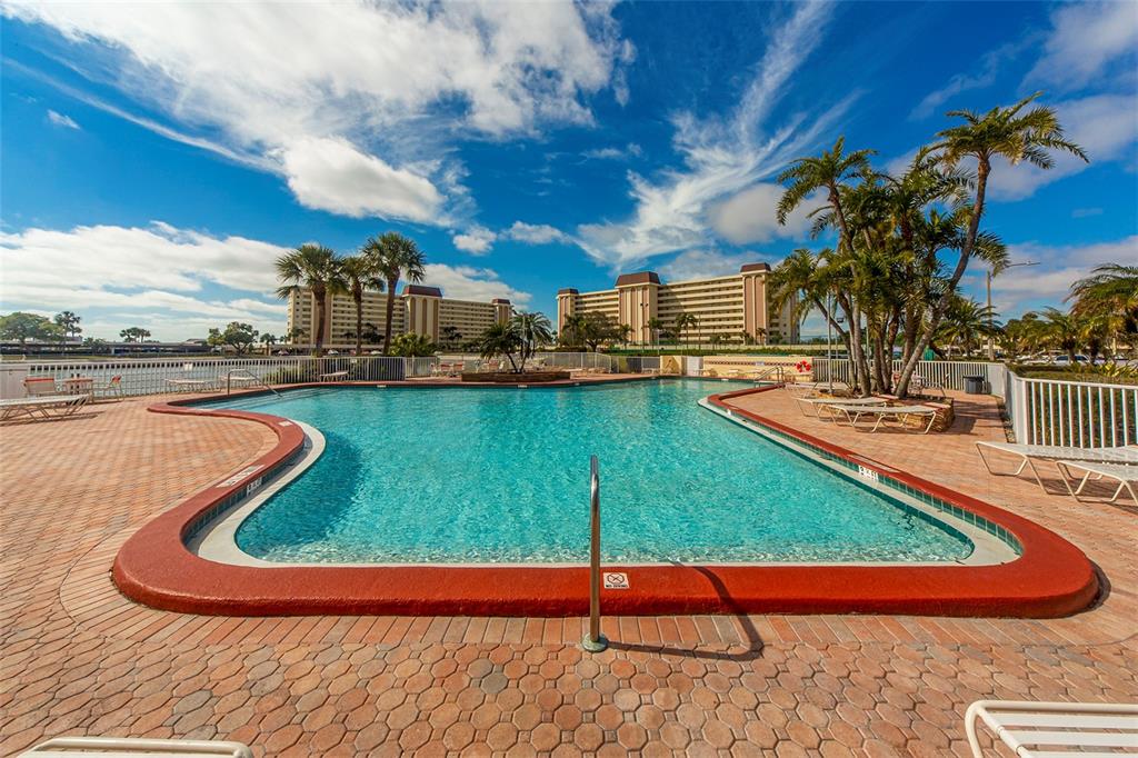 4775 Cove Circle, Unit 1202 Madeira Beach, FL 33708 - Photo 27 of 32 a view of a swimming pool with a lounge chairs