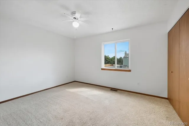 an empty room with closet and a ceiling fan