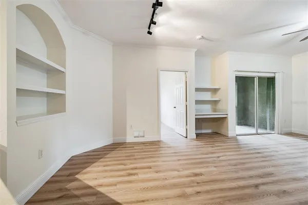 a view of an empty room with a window and a kitchen