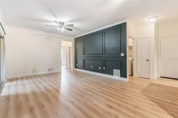 an empty room with wooden floor chandelier fan and windows