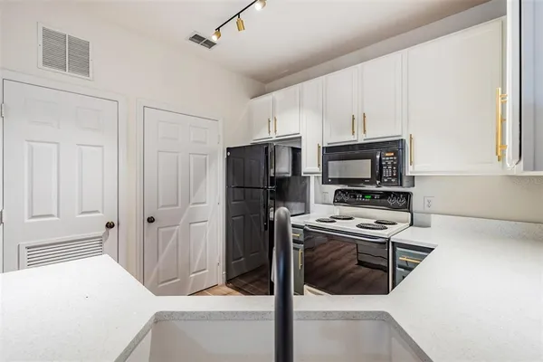 a view of kitchen and empty room with wooden floor