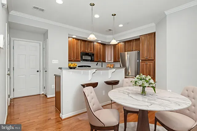 a kitchen with stainless steel appliances granite countertop a sink dishwasher a stove top oven a refrigerator with wooden cabinets and floor