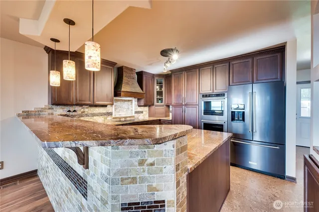 a kitchen with stainless steel appliances granite countertop a sink a refrigerator and a stove