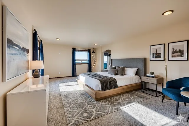 a spacious bedroom with a bed a table and painting on the wall