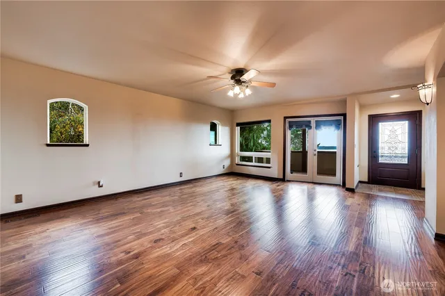 a view of an empty room with window and wooden floor