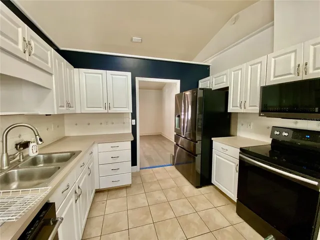 a kitchen with granite countertop a refrigerator and a stove top oven