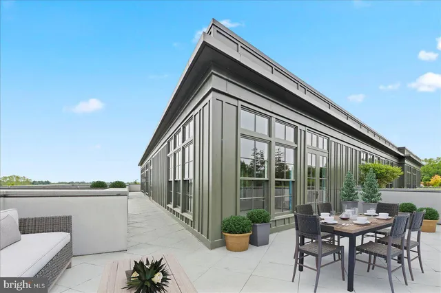 a roof deck with table and chairs and potted plants