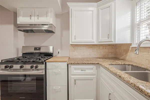 a kitchen with granite countertop stainless steel appliances a stove and a sink