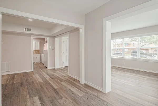 a view of an empty room with wooden floor and a window