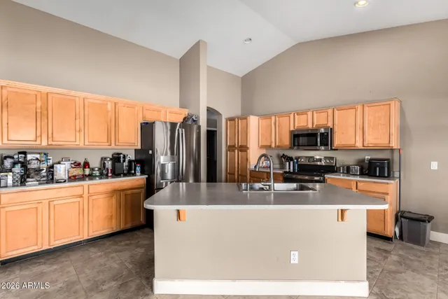 a kitchen with stainless steel appliances a stove a sink a refrigerator a center island cabinets and furniture