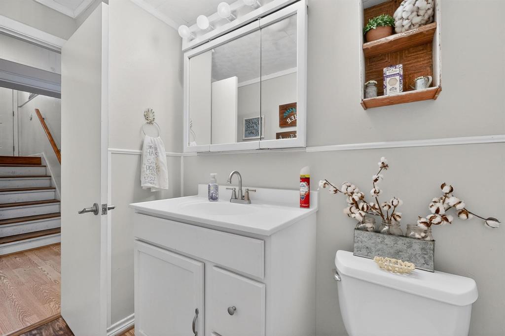 202 Senter Valley Road Irving, TX 75060 - Photo 9 of 32 Bathroom featuring a white vanity with integrated sink, chrome faucet, wall-mounted mirrored medicine cabinet with vanity lighting, and wainscoting