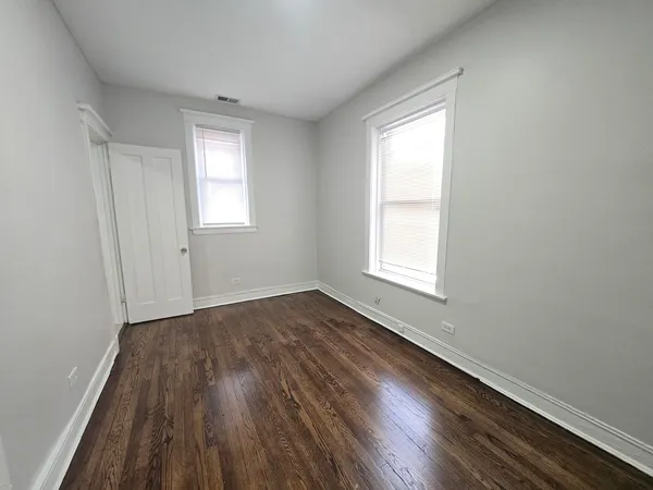 a view of an empty room with wooden floor and closet