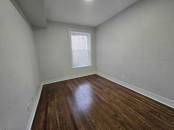 a view of an empty room with wooden floor and closet