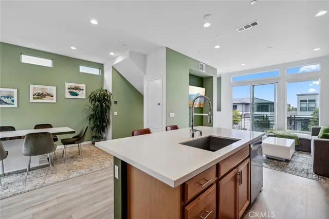 a large kitchen with kitchen island granite countertop a stove a sink a dining table and chairs