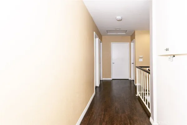 a view of a hallway with wooden floor and a bathroom
