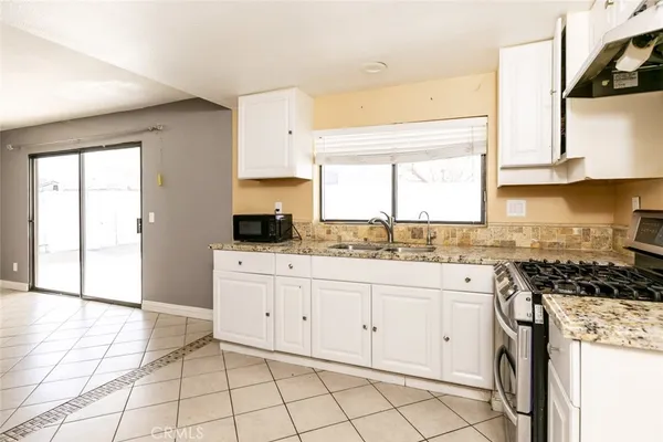 a kitchen with granite countertop white cabinets a stove a sink and a window