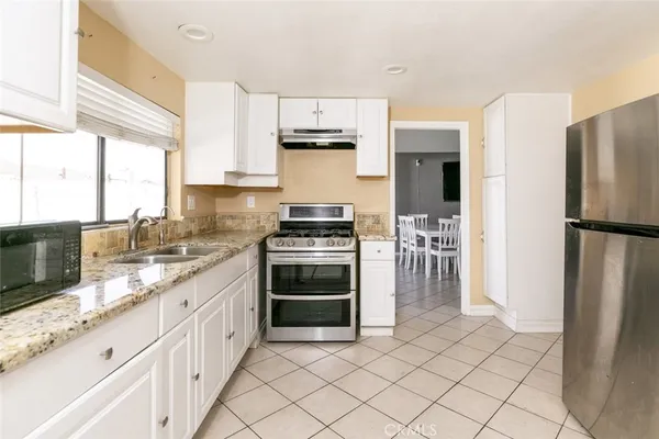 a kitchen with granite countertop a refrigerator stove and sink