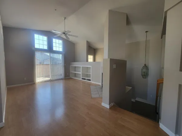 an empty room with wooden floor cabinet and windows