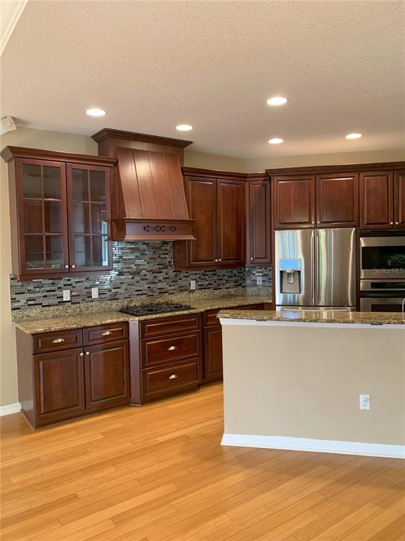 6828 Honeysuckle Trail Lakewood Ranch, FL 34202 - Photo 11 of 36 a kitchen with stainless steel appliances granite countertop a sink a stove a refrigerator cabinets and wooden floor