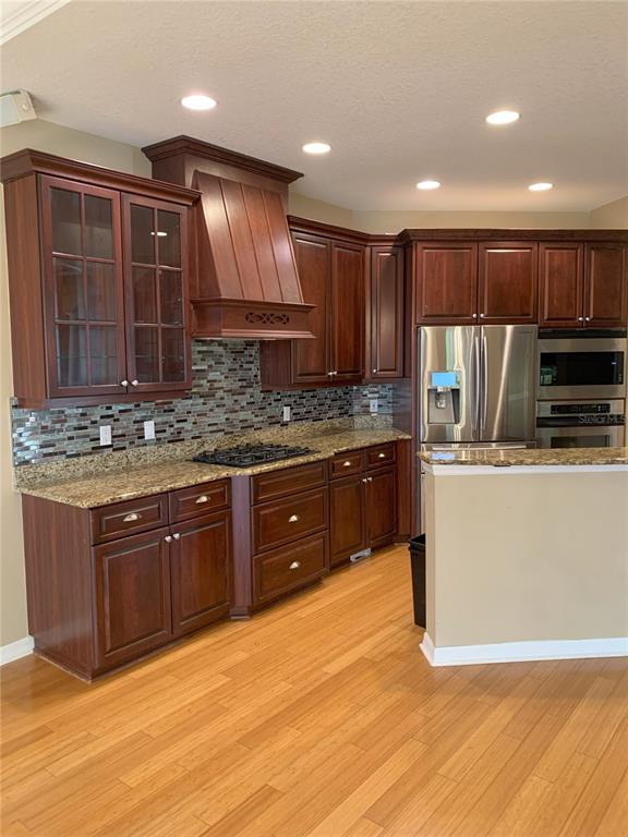 6828 Honeysuckle Trail Lakewood Ranch, FL 34202 - Photo 12 of 36 a kitchen with kitchen island granite countertop wooden cabinets stainless steel appliances a sink and a counter top space
