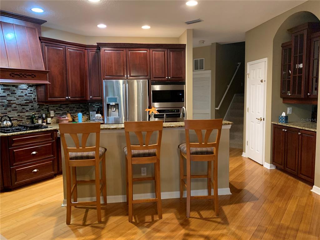 6828 Honeysuckle Trail Lakewood Ranch, FL 34202 - Photo 13 of 36 a kitchen with granite countertop wooden cabinets and stainless steel appliances