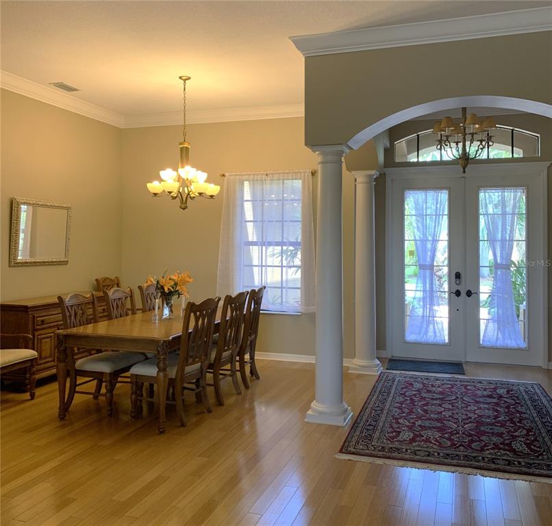 6828 Honeysuckle Trail Lakewood Ranch, FL 34202 - Photo 9 of 36 a view of a dining room with furniture a chandelier and wooden floor