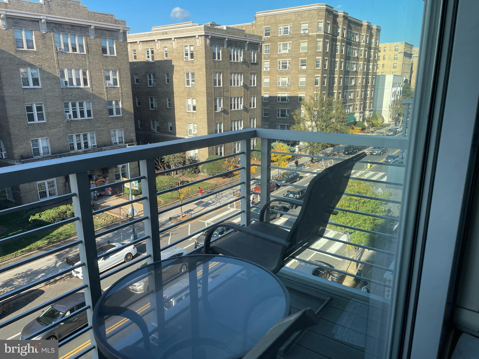 a view of a balcony with a floor to ceiling window next to a tall building